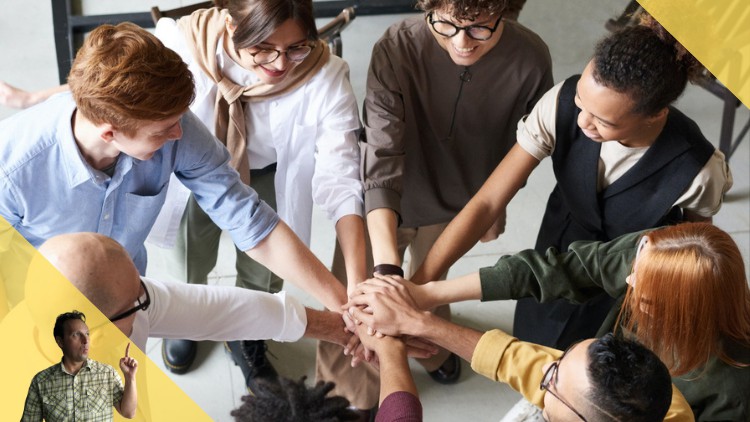 7 people in a circle with their hands joined in the middle.