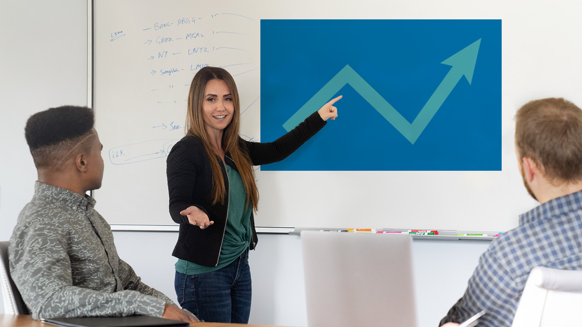 A woman presenting to a team of people at a white board.
