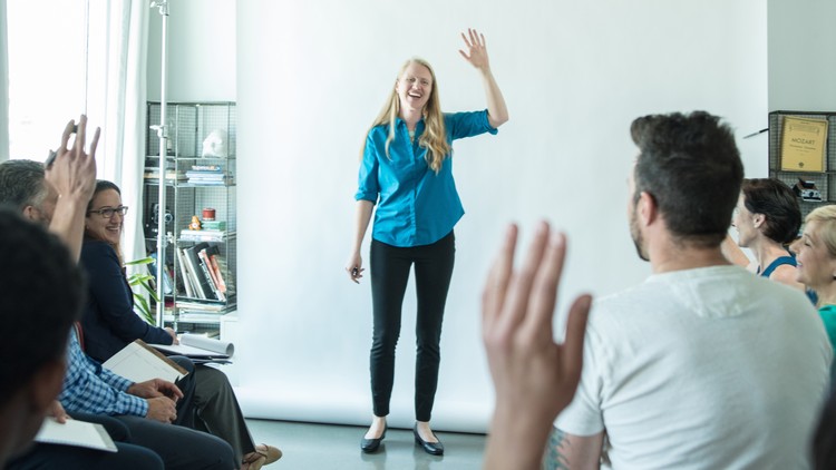 A woman smiles while presenting to a small group