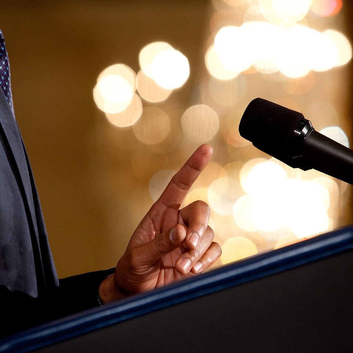 A podium, a microphone, and a speaker's hand.