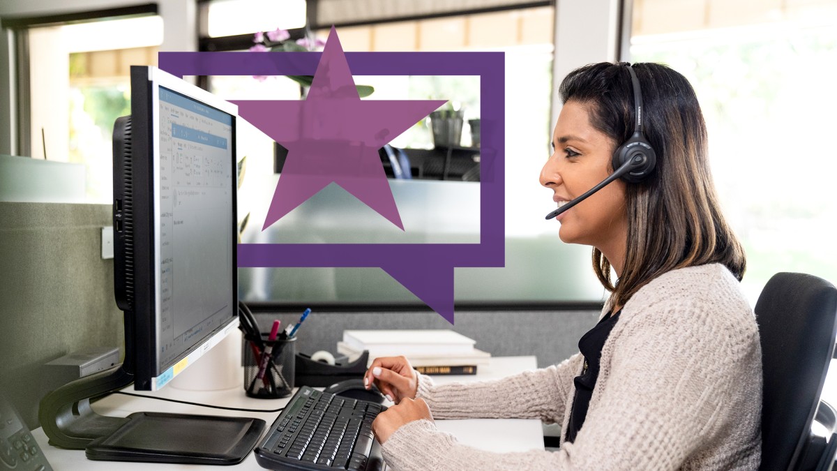 A customer service representative smiles while talking on a headset and looking at a computer screen.