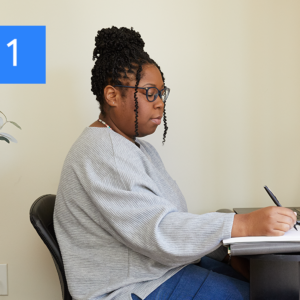 A woman writes at a table.