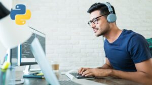 a man works on a computer while wearing headphones.